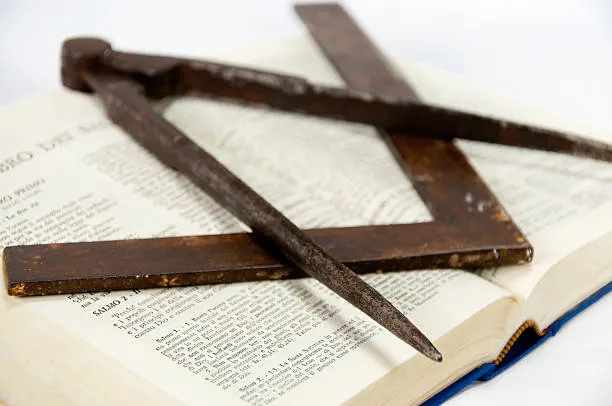 Square and compasses resting on an open book